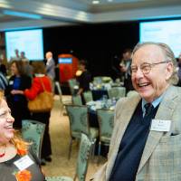 Guest laughing while chatting with two other guests at Scholarship Dinner 2019